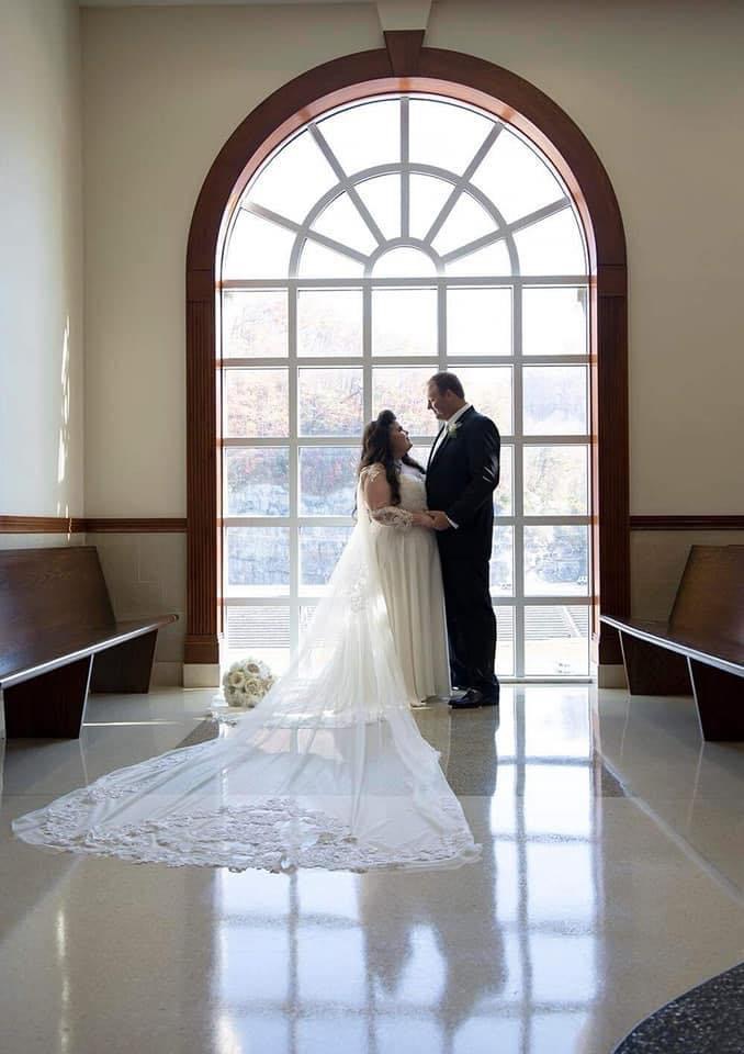 Bride and groom under arched chapel window