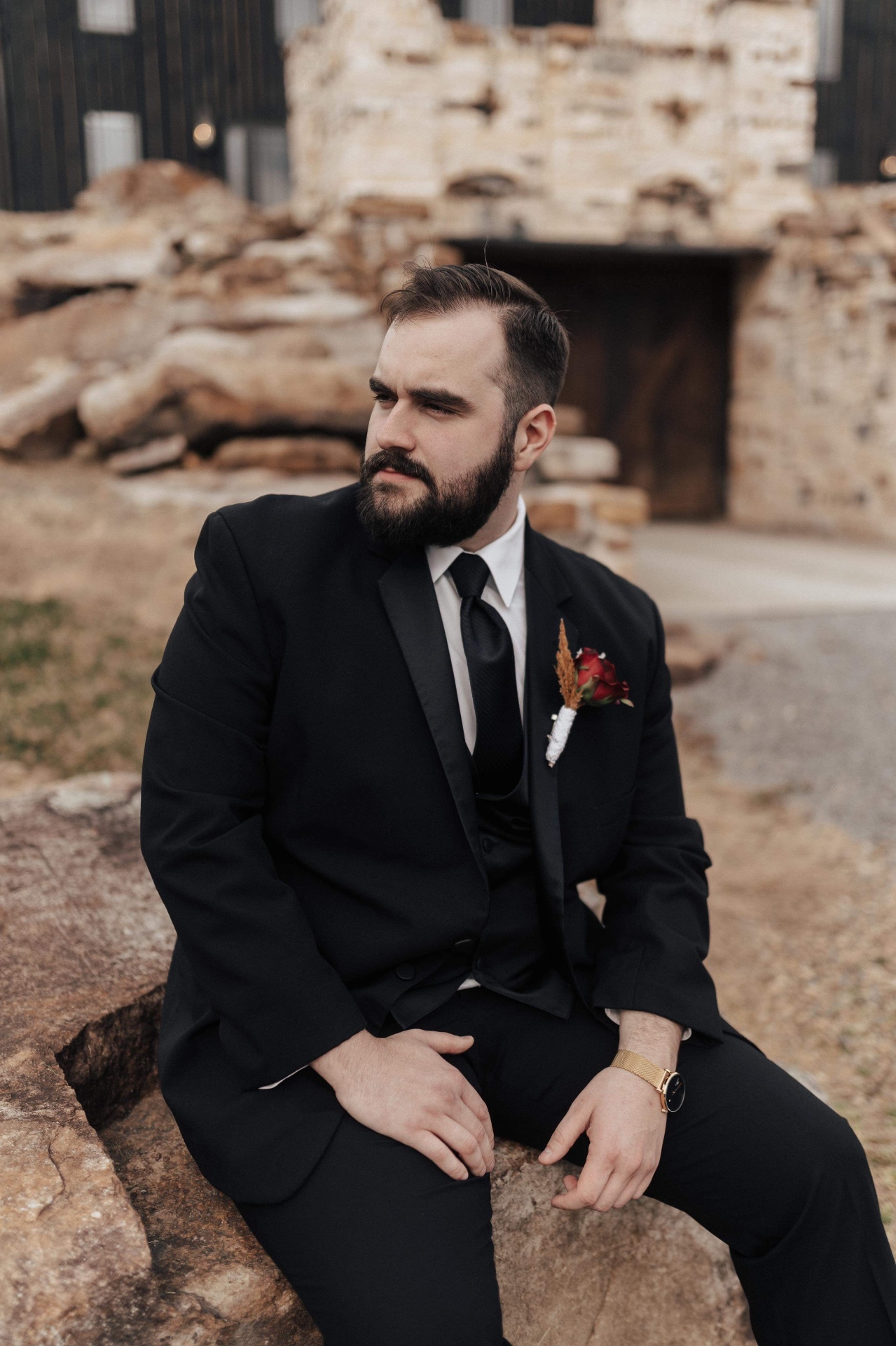 Groom in classic black three-piece tuxedo with red rose boutonnière